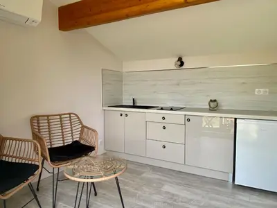 a kitchen with white cabinets and a table and chairs at Entre Pins et Romarins in Bizanet