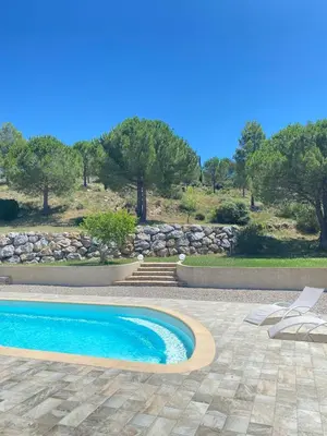 a swimming pool in a yard with chairs and trees at Entre Pins et Romarins in Bizanet