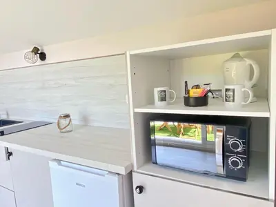 a kitchen with a cupboard with a microwave in it at Entre Pins et Romarins in Bizanet
