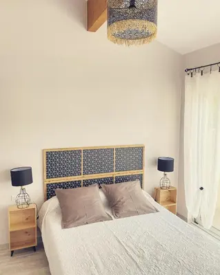 a bedroom with a bed and two lamps and a chandelier at Entre Pins et Romarins in Bizanet