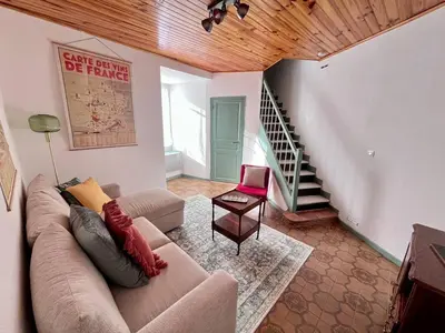 a living room with a couch and a staircase at Le Nid de l'Abbaye - Maison de charme rénovée in Saint-Hilaire