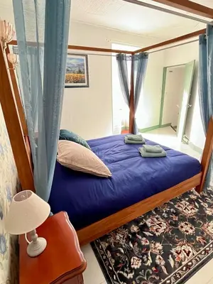a bedroom with a bed with a blue comforter at Le Nid de l'Abbaye - Maison de charme rénovée in Saint-Hilaire
