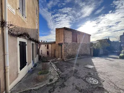 a building with a water fountain next to a building at Le Nid de l'Abbaye - Maison de charme rénovée in Saint-Hilaire