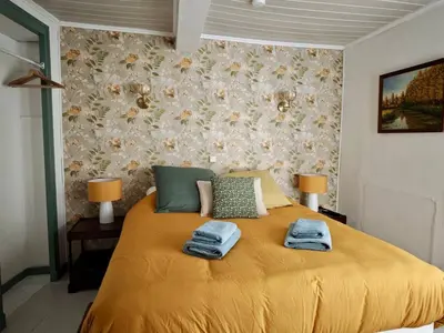 a bedroom with a yellow bed with towels on it at Le Nid de l'Abbaye - Maison de charme rénovée in Saint-Hilaire