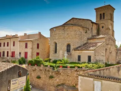 an old stone building with a tower and a church at Le Nid de l'Abbaye - Maison de charme rénovée in Saint-Hilaire
