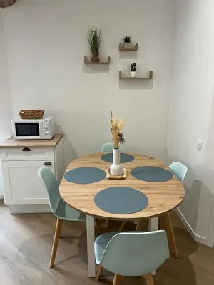 a kitchen with white cabinets and a table with chairs at L'Appart cosy 52m2 avec local à vélo près du Canal du Midi in Capestang