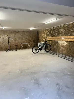 a garage with a black door in a white building at L'Appart cosy 52m2 avec local à vélo près du Canal du Midi in Capestang