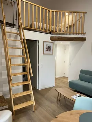 a living room with a bunk bed and a living room with a table at L'Appart cosy 52m2 avec local à vélo près du Canal du Midi in Capestang