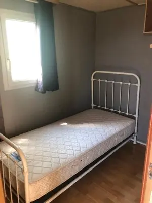a small bed in a room with a window at appartement, deux chambres in Damiatte
