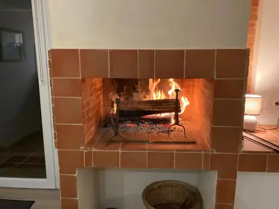 a brick fireplace with a fire in it at Charmant studio avec vue sur le château de Montségur in Montferrier