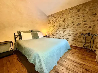 a bedroom with a bed and a stone wall at Farmhouse With Cathedral Lounge And Sauna In Pines in Cases-de-Pène
