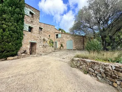 an old stone house with a stone wall and a driveway at Farmhouse With Cathedral Lounge And Sauna In Pines in Cases-de-Pène