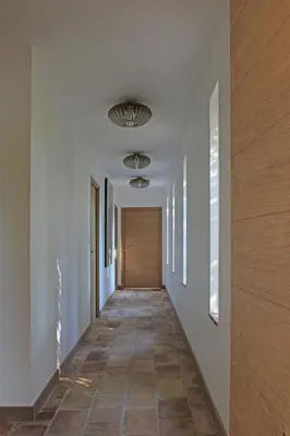a hallway with white walls and a wooden door at Accessible Villa In The Heart Of Corbières in Marcorignan