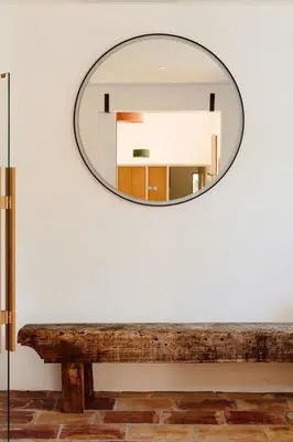 a mirror hanging on a wall next to a wooden bench at Accessible Villa In The Heart Of Corbières in Marcorignan