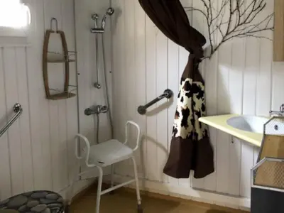 a bathroom with a shower and a chair and a sink at Chalet PMR avec Terrasse pour 4 Pers, Roquefeuil - API-1-52-139 in Roquefeuil