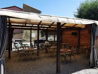 a group of tables and chairs under a pavilion at Chalet PMR avec Terrasse pour 4 Pers, Roquefeuil - API-1-52-139 in Roquefeuil