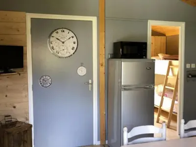 a clock on a wall next to a refrigerator at Chalet PMR avec Terrasse pour 4 Pers, Roquefeuil - API-1-52-139 in Roquefeuil