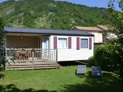 a tiny house with a porch and a deck at Mobil-home confort pour 4 personnes avec terrasse - API-1-52-115 in Roquefeuil