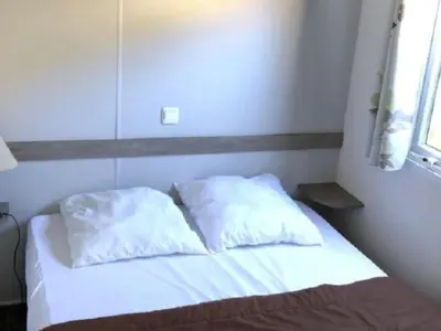 a bed with two pillows on it in a room at Mobil-home confort pour 4 personnes avec terrasse - API-1-52-115 in Roquefeuil