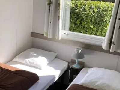 a small room with two beds and a window at Mobil-home confort pour 4 personnes avec terrasse - API-1-52-115 in Roquefeuil