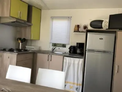 a kitchen with a refrigerator and two chairs in it at Mobil home confortable avec 3 chambres et terrasse à Roquefeuil - API-1-52-142 in Roquefeuil