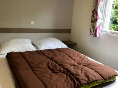 a bed with a brown comforter in a bedroom at Mobil home confortable avec 3 chambres et terrasse à Roquefeuil - API-1-52-142 in Roquefeuil