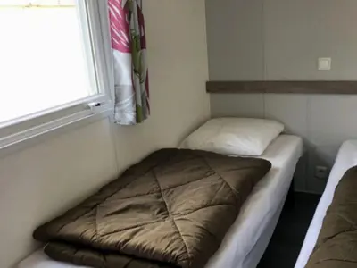 a small room with a bed and a window at Mobil home confortable avec 3 chambres et terrasse à Roquefeuil - API-1-52-142 in Roquefeuil