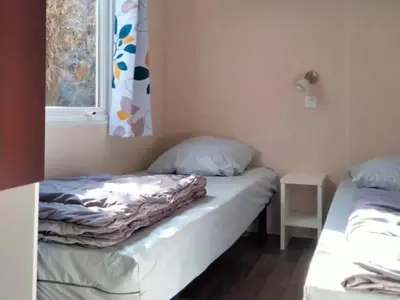two beds in a small room with a window at Mobil-Home 2 Chambres avec Terrasse - API-1-52-1325 in Vielmur-sur-Agout