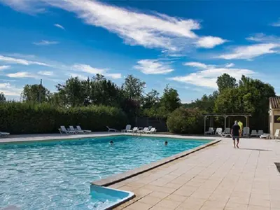 a person walking by a swimming pool at Mobil-Home 2 Chambres avec Terrasse - API-1-52-1325 in Vielmur-sur-Agout