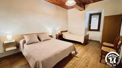 a bedroom with a bed and a chair and a window at Laguzou in Saint-Julien-de-Briola