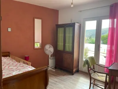 a bedroom with a bed and a table and a window at Maison idéalement située au milieu des vignes in Planèzes