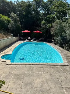 a large blue swimming pool with two umbrellas at Nature stay, French Villa in Villarzel-du-Razès