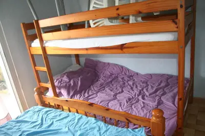 a wooden bunk bed with a purple pillow on it at Port La Nouvelle T2 rez de chaussée idéal pour 4 personnes in Port-la-Nouvelle