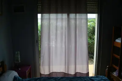 a window with a white curtain in a bedroom at Port La Nouvelle T2 rez de chaussée idéal pour 4 personnes in Port-la-Nouvelle