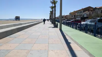 a person walking down a sidewalk next to the beach at Port La Nouvelle T2 rez de chaussée idéal pour 4 personnes in Port-la-Nouvelle