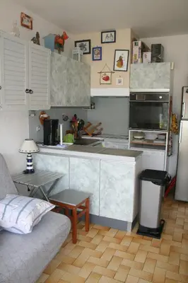 a kitchen with a counter and a couch in a room at Port La Nouvelle T2 rez de chaussée idéal pour 4 personnes in Port-la-Nouvelle