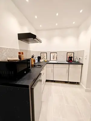 a kitchen with a black counter top and white cabinets at LE COSY - Studio 4 pers - wifi - centre ville in Limoux