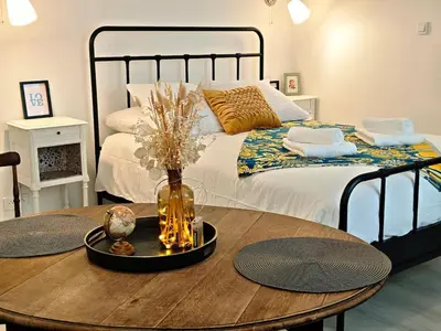 a bedroom with a bed with a wooden table with a vase at LE COSY - Studio 4 pers - wifi - centre ville in Limoux