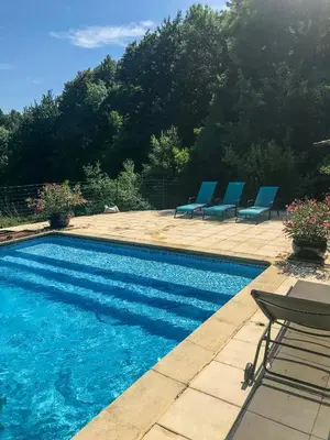 a swimming pool with blue chairs next to a patio at Old Farmhouse Surrounded By Nature In Sidobre in Burlats