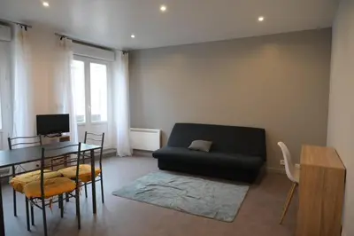 a living room with a black couch and a table at Le Nid Central - Lumineux et confort, cœur Mazamet in Mazamet