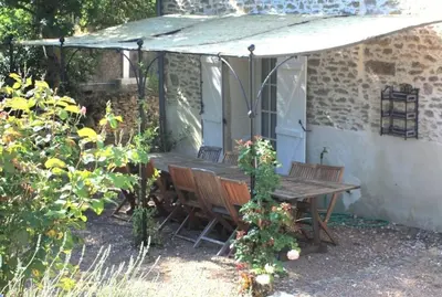 a wooden table and chairs under an umbrella at La Bomba Is A Stunning Farmhouse in Glorious Countryside With Private Pool in Saint-Paulet