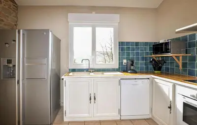 a kitchen with white cabinets and a sink and a window at Authentique Maison Piscine in Saint-Amans-Valtoret