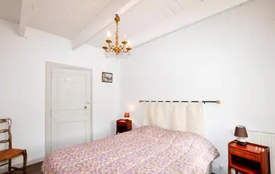 a bedroom with a bed and a chandelier at Authentique Maison Piscine in Saint-Amans-Valtoret