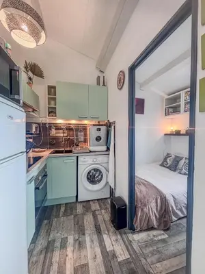 a small kitchen with a bed and a washer at Charmant T2 & Mezzanine Idéal pour un séjour à Gruissan in Gruissan