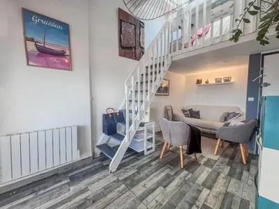 a living room with a staircase and a couch at Charmant T2 & Mezzanine Idéal pour un séjour à Gruissan in Gruissan
