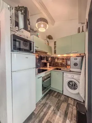 a kitchen with green cabinets and a washer and dryer at Charmant T2 & Mezzanine Idéal pour un séjour à Gruissan in Gruissan