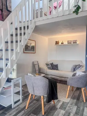 a living room with a couch under a stairs at Charmant T2 & Mezzanine Idéal pour un séjour à Gruissan in Gruissan