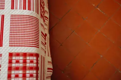 a red and white quilt on a wall at Le Tamaroque in Portel-des-Corbières