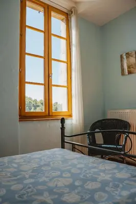 a bedroom with a bed and a window and a chair at Le Tamaroque in Portel-des-Corbières