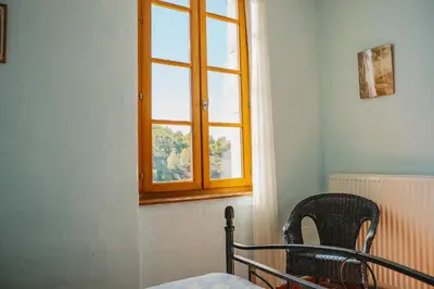 a window in a room with a bed and a chair at Le Tamaroque in Portel-des-Corbières